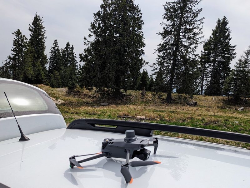 Survey drone on a car bonnet in front of spruce forest